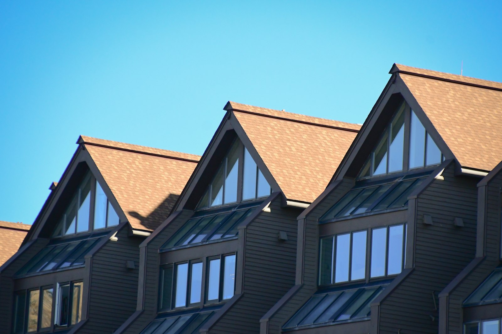 Three steep dormer gables against a clear blue sky
