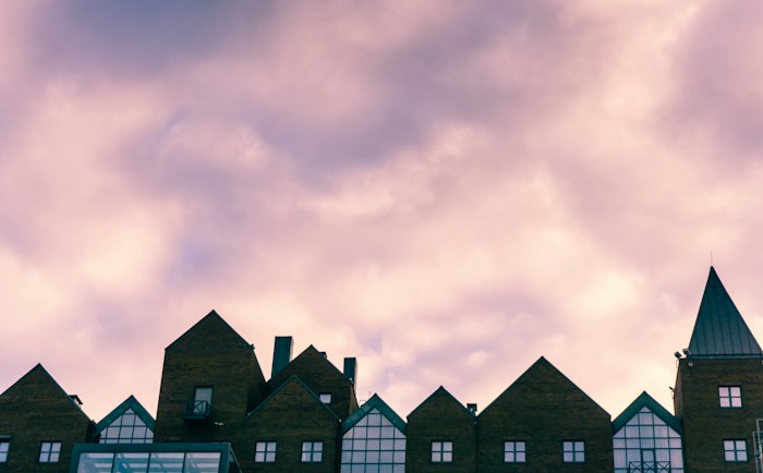 Gabled rooftops silhouetted against a pink sky